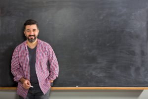 male teacher standing in front of chalkboard