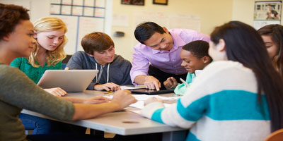 students sitting at table learning from teacher