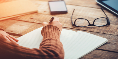 woman writing at a wooden table