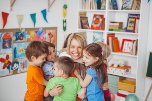 preschool teacher hugging group of students