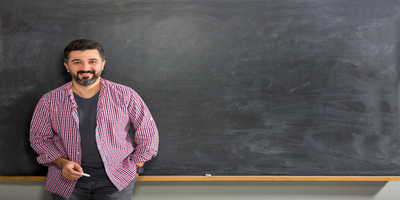 male teacher leaning against chalkboard