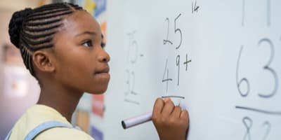 Girl doing a math problem on a whiteboard