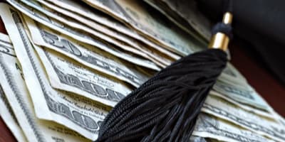 graduation tassel placed over dollar bills