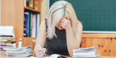 teacher with her head in her hands while she's grading papers