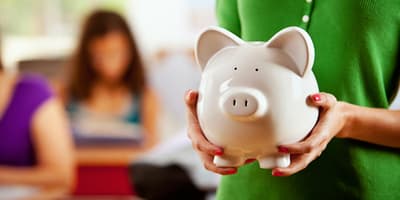 woman holding piggy bank with children in the background