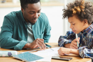 Male teacher helping young boy with school work